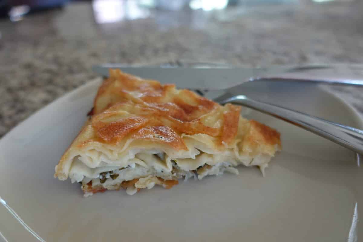A sliced piece of Su Böreği on a white plate ready to be served