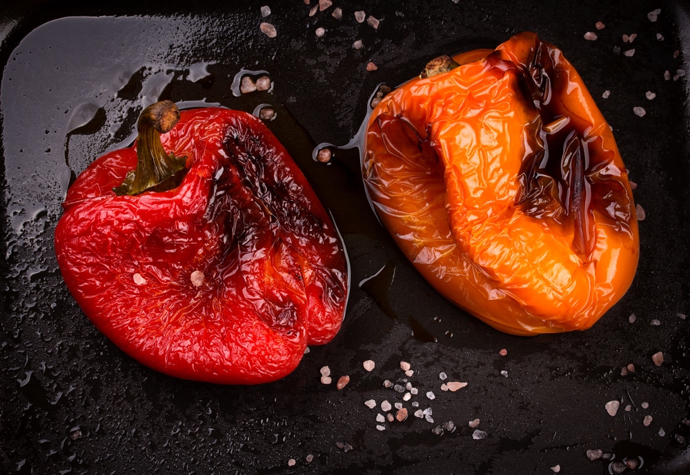 Two beautifully roasted peppers, one red and one orange.