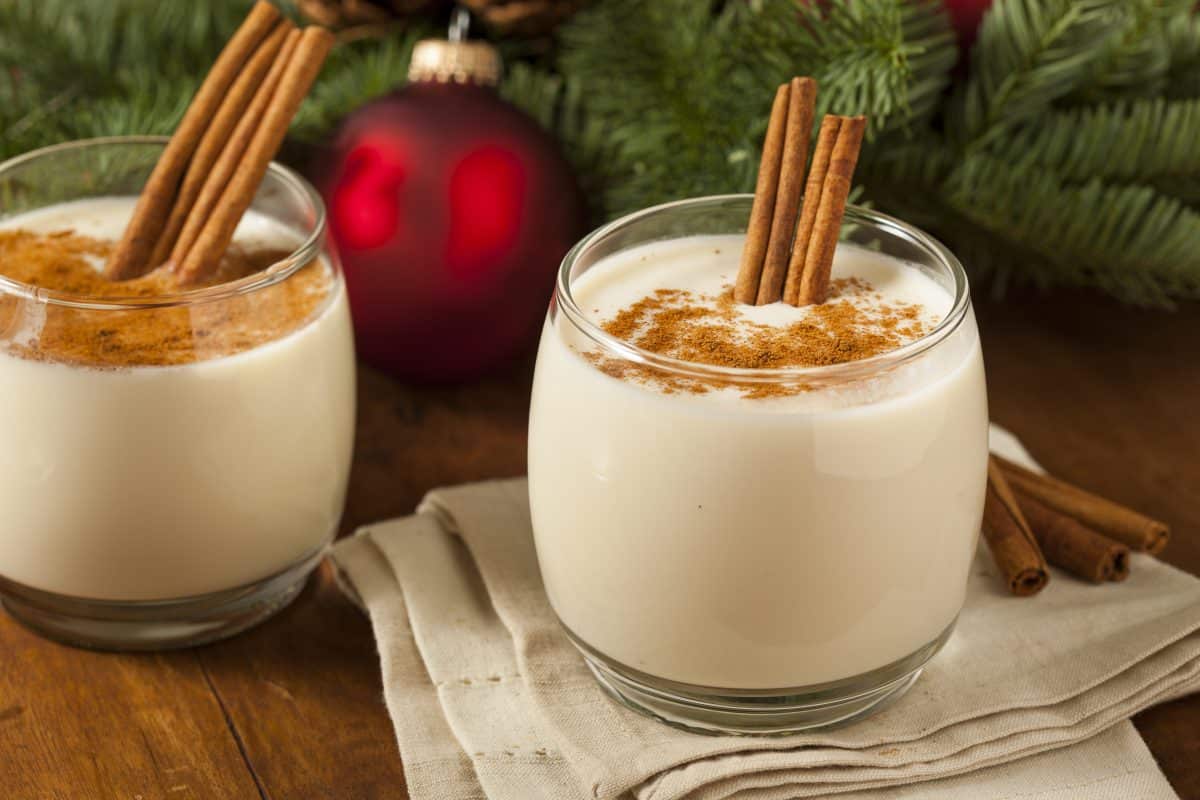 Two glasses of Ron Ponche Panamanian eggnog with cinnamon sticks.