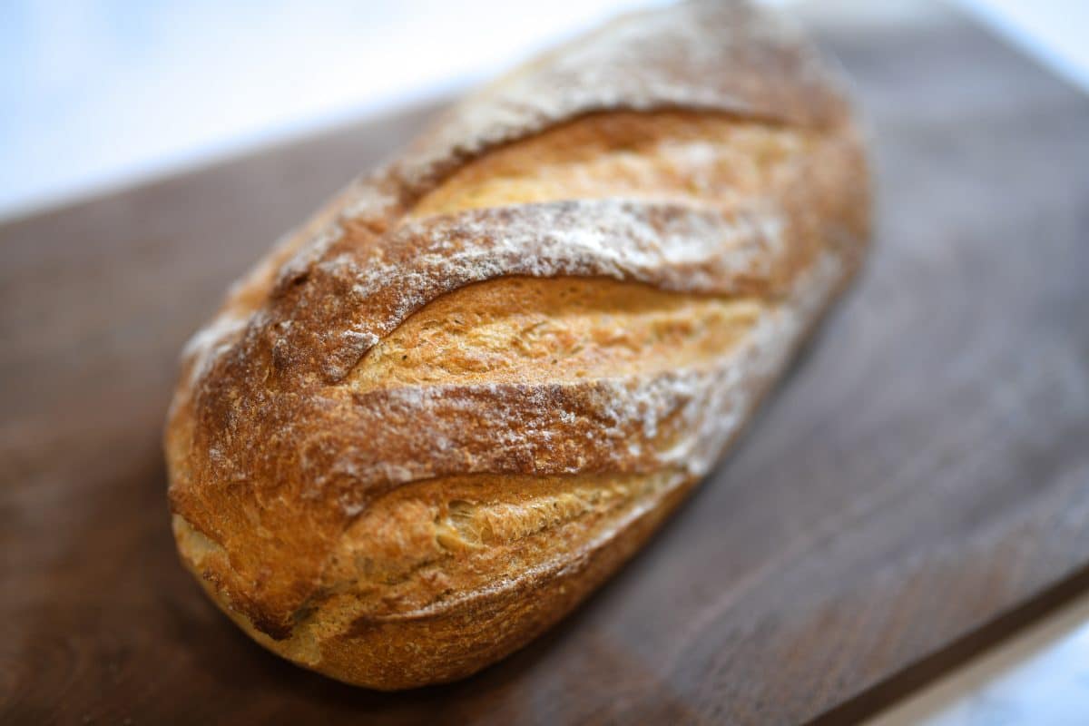 A close-up of a rustic bread loaf on a wooden surface.