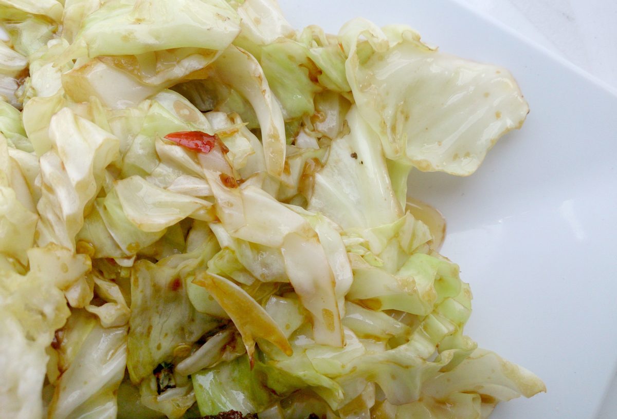 Close-up of a white plate with stir-fried cabbage.