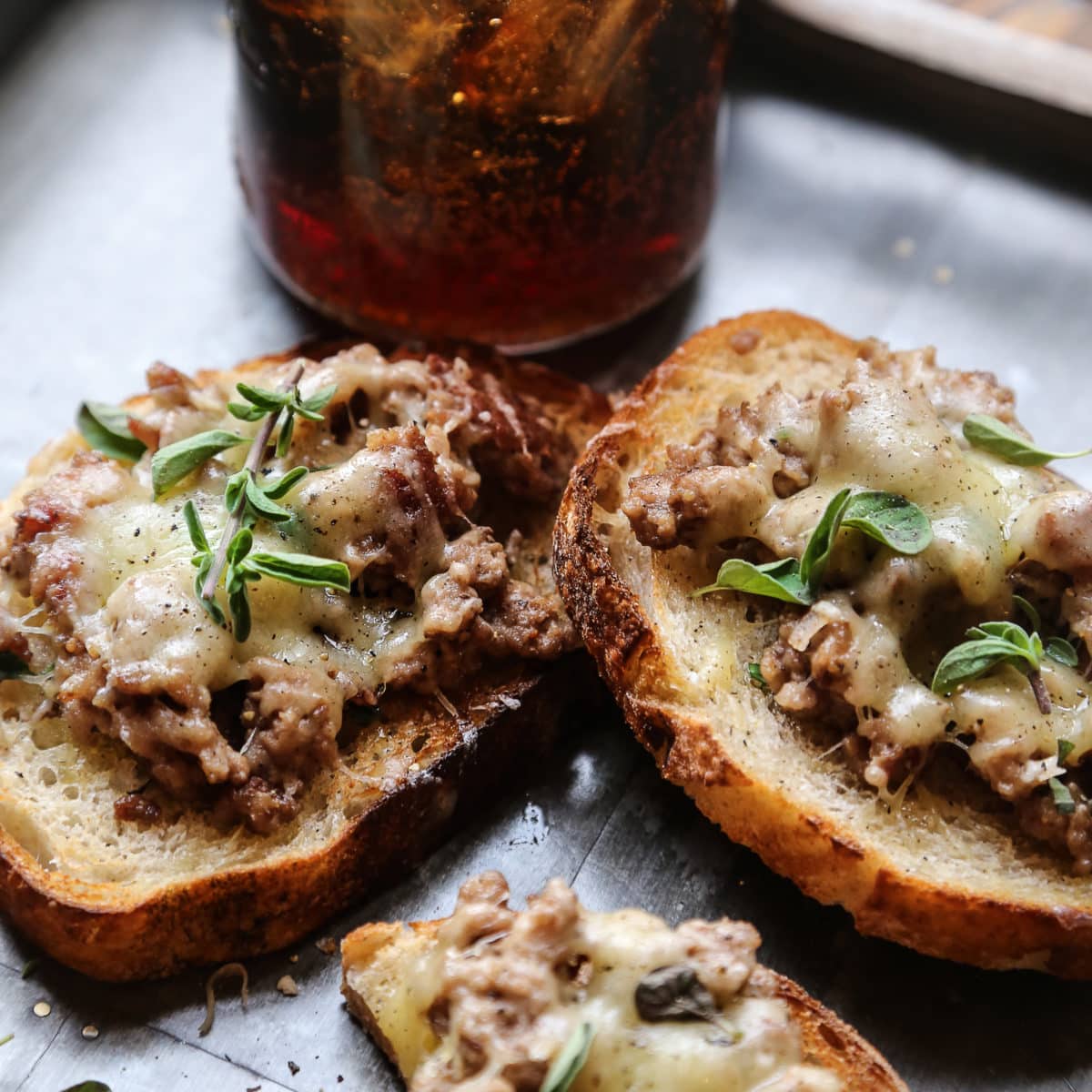 An open faced sandwich with sautéed sausage and melted cheese.