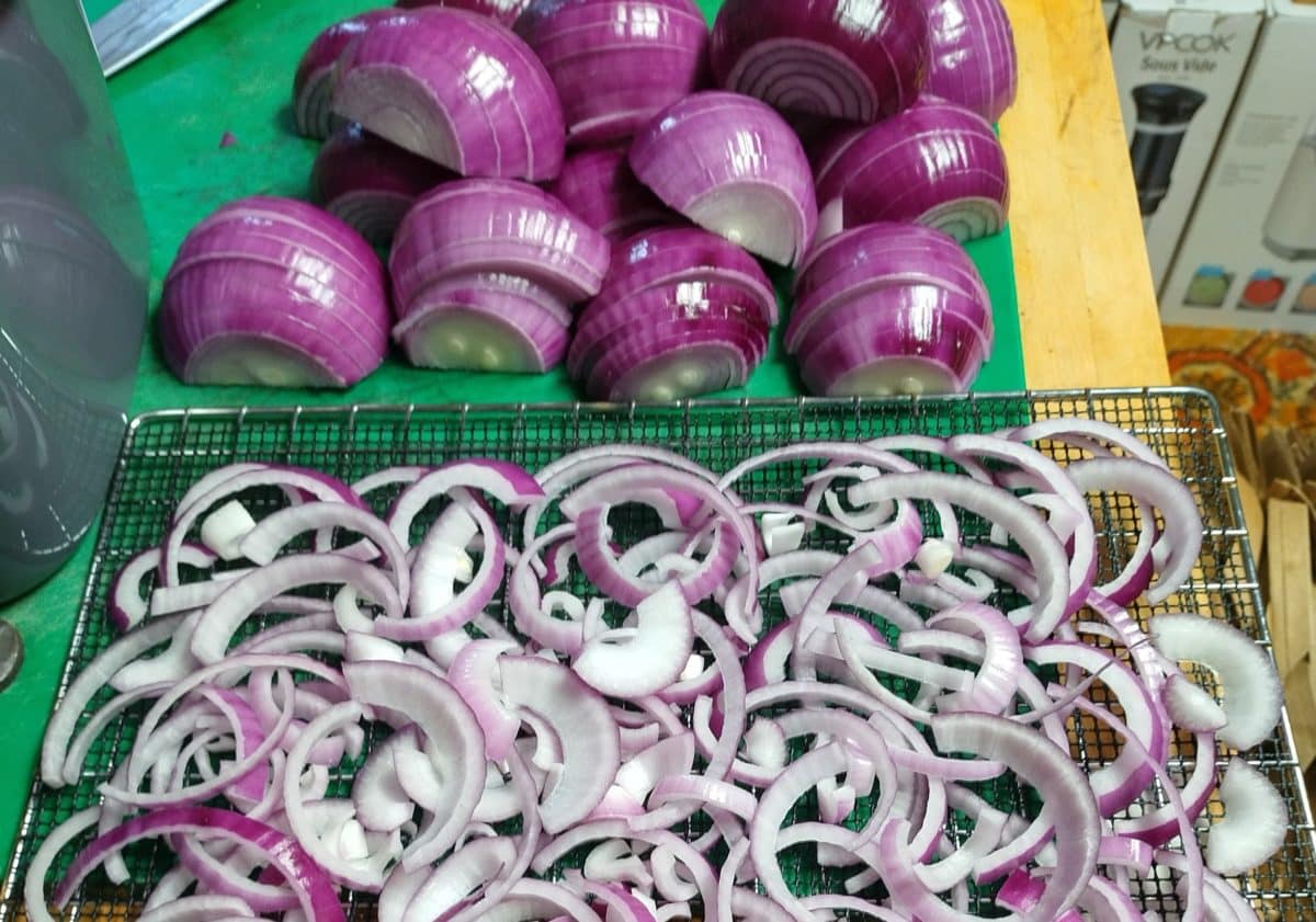 Whole and sliced red onions on a table.