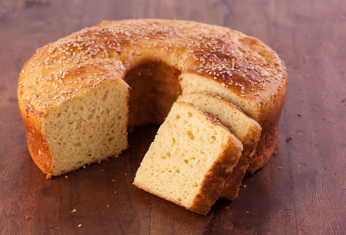 Close-up of a round loaf of challah, with several sliced pieces.