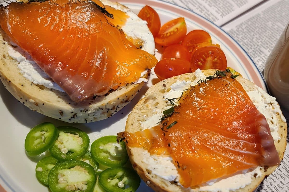 Thin slices of cured salmon placed on a half-eaten bread roll.