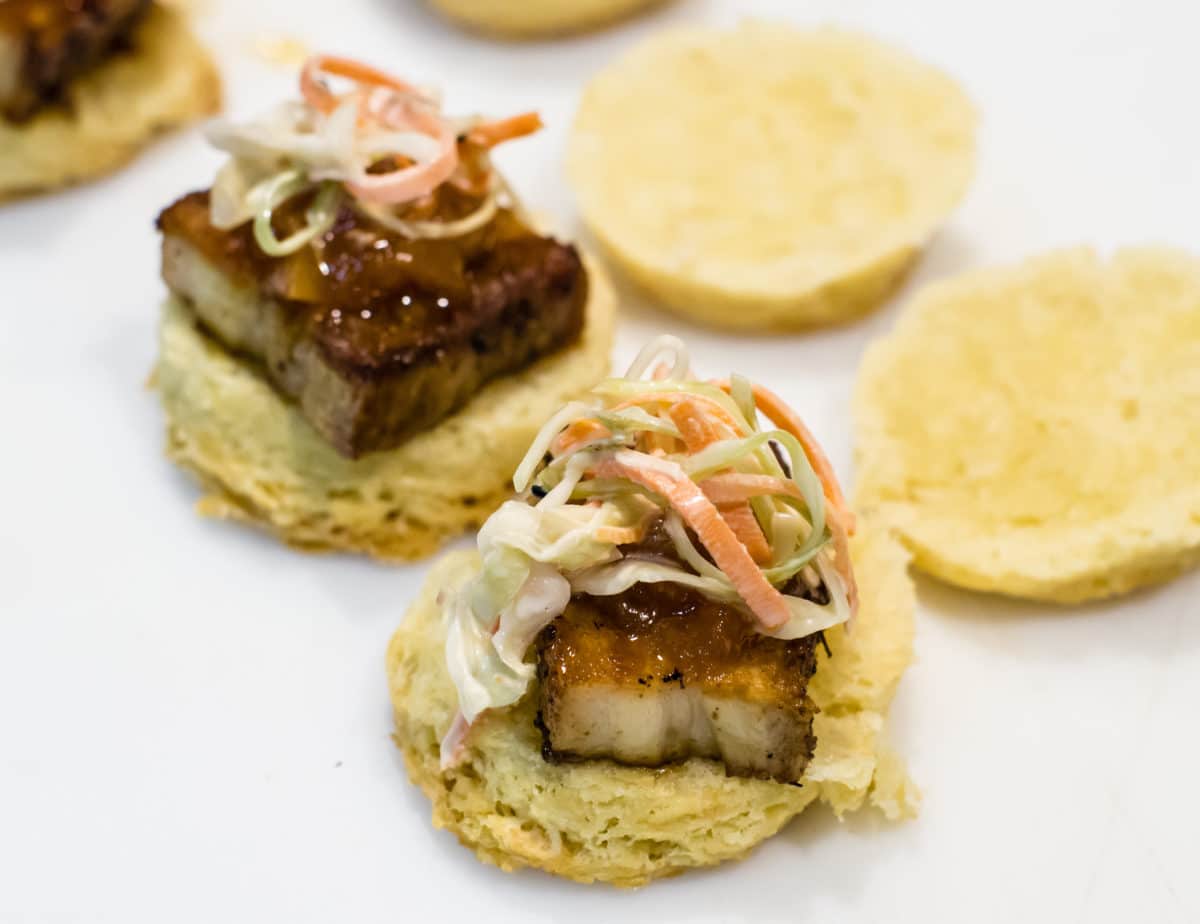 Pork sliders topped with a fresh coleslaw, served on soft buns.