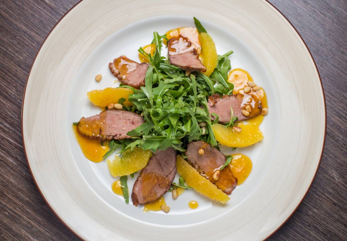Sliced smoked duck over a salad with orange segments and a tangy Asian dressing.