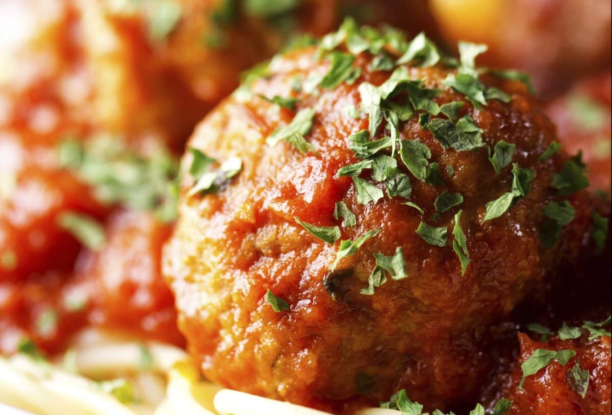 Close-up of a meatball with tomato sauce and sprinkled parsley