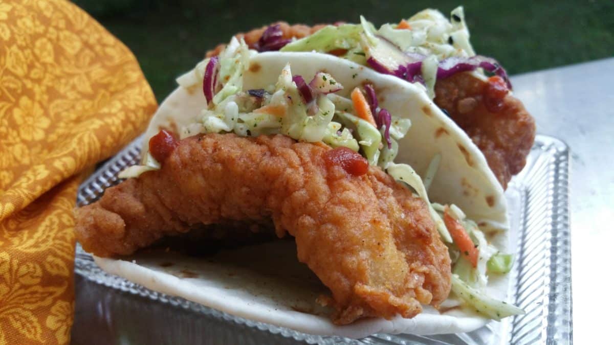 A Southern style fish taco filled with fried fish and Hawaiian slaw, garnished with vegetables.