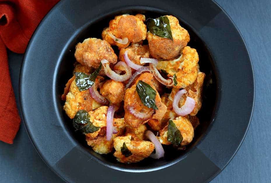 A bowl of spicy baked cauliflower florets with onions and curry leaves