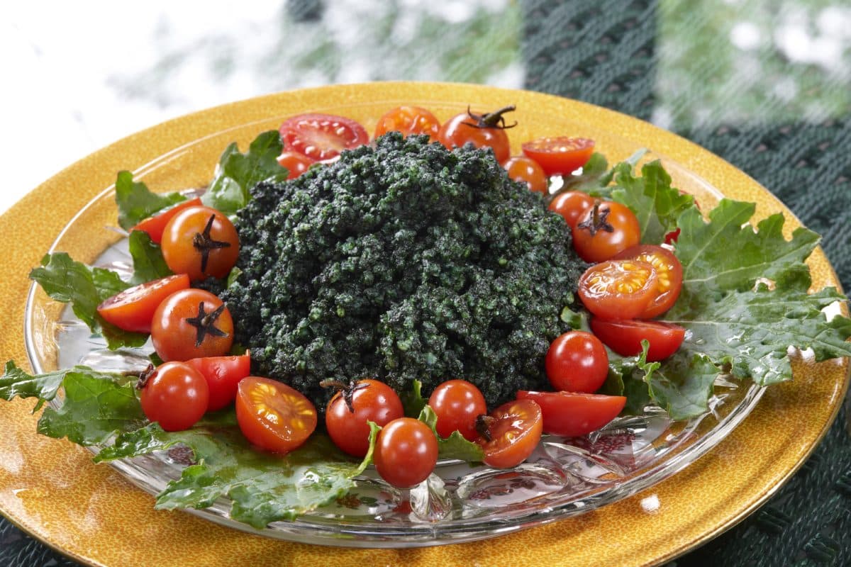 Fresh spirulina millet salad on a plate garnished with tomatoes.