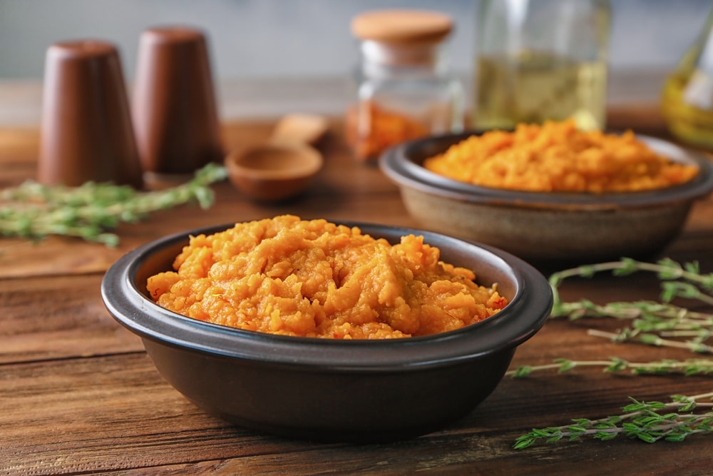 A close-up of a dish made with squash and yam, accompanied by kitchen condiments.