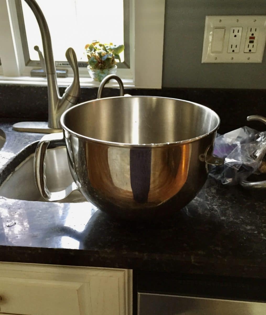Stainless steel mixing bowl on a dark marble kitchen counter.