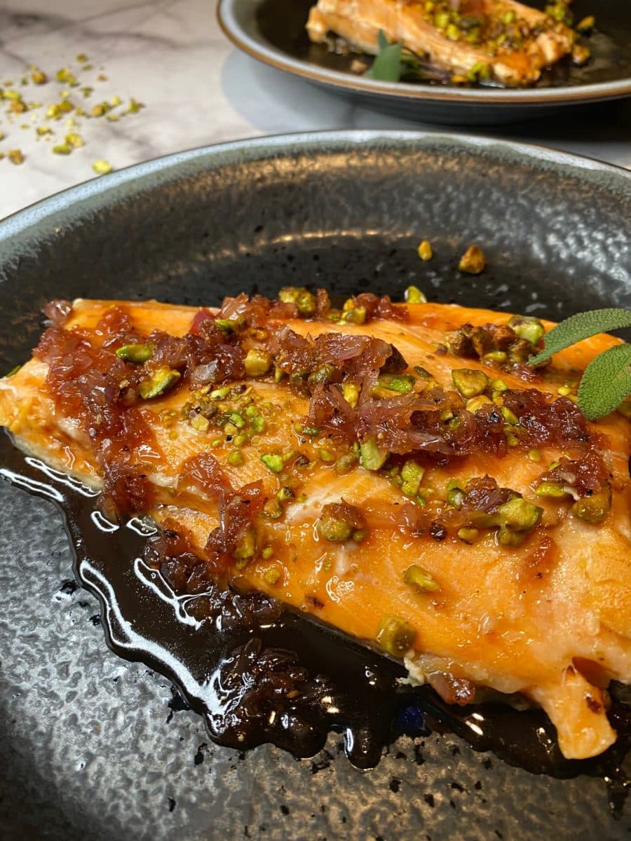 Sous vide steelhead trout with garnish on a plate.