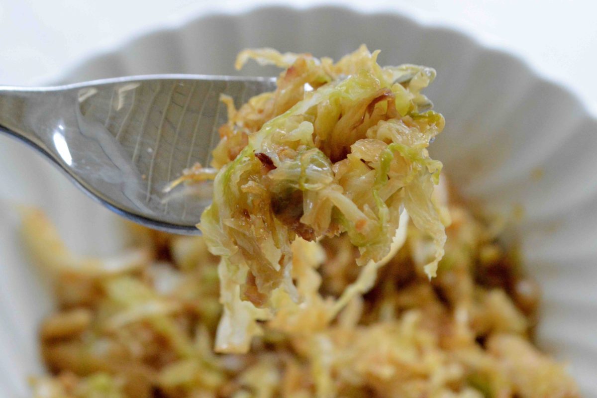 A close-up of sweet and spicy stir-fried cabbage on a fork.