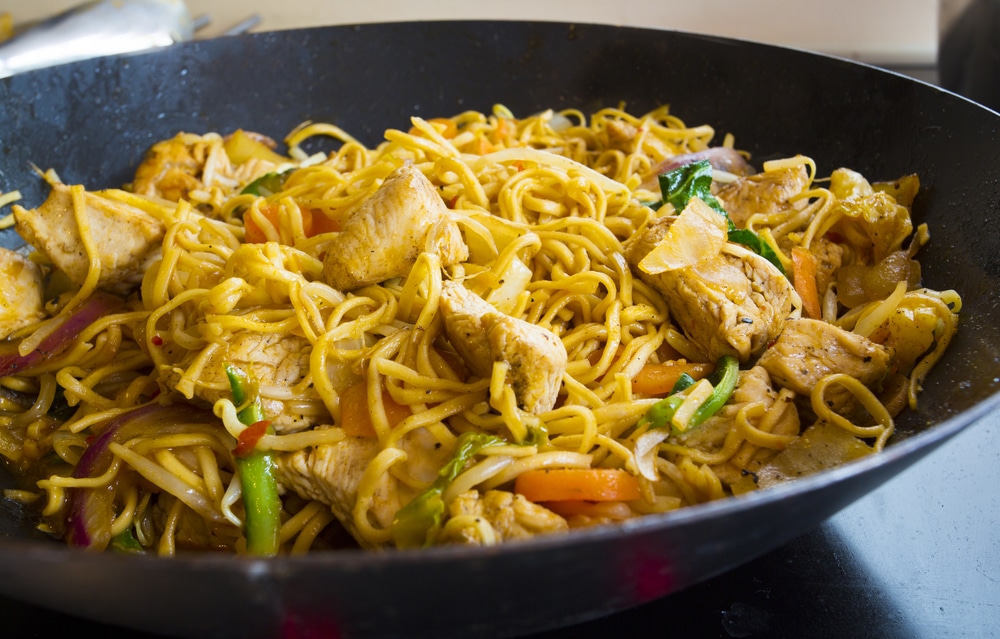 Stir-fry noodles with chicken and vegetables in a black wok