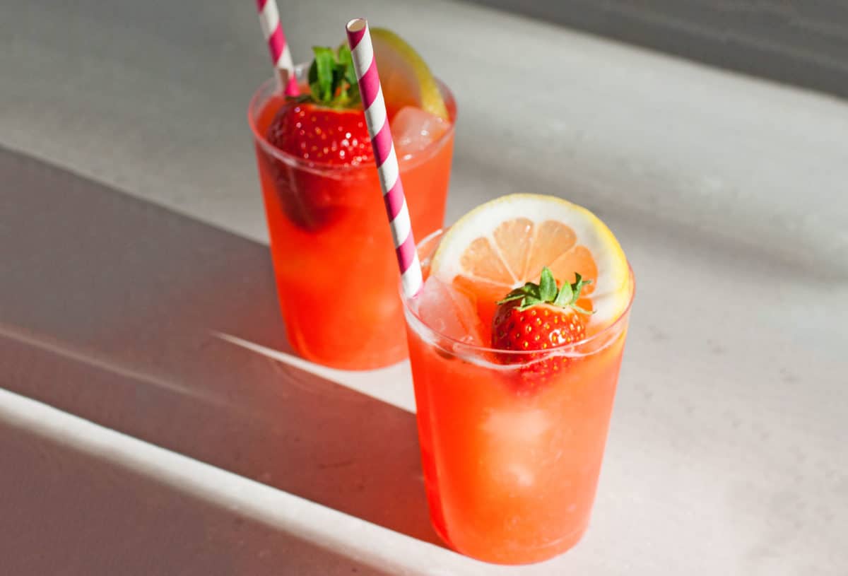 Two glasses of strawberry lemonade with ice.