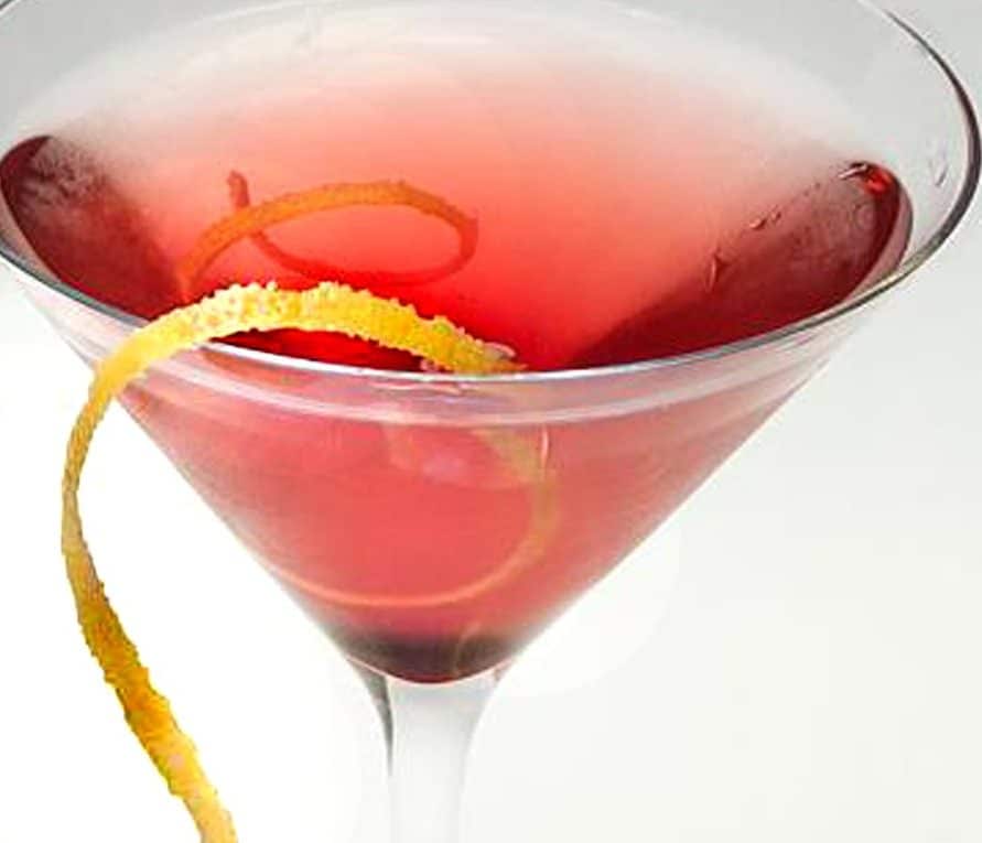 Close-up of a black currant martini with a spiral citrus peel.