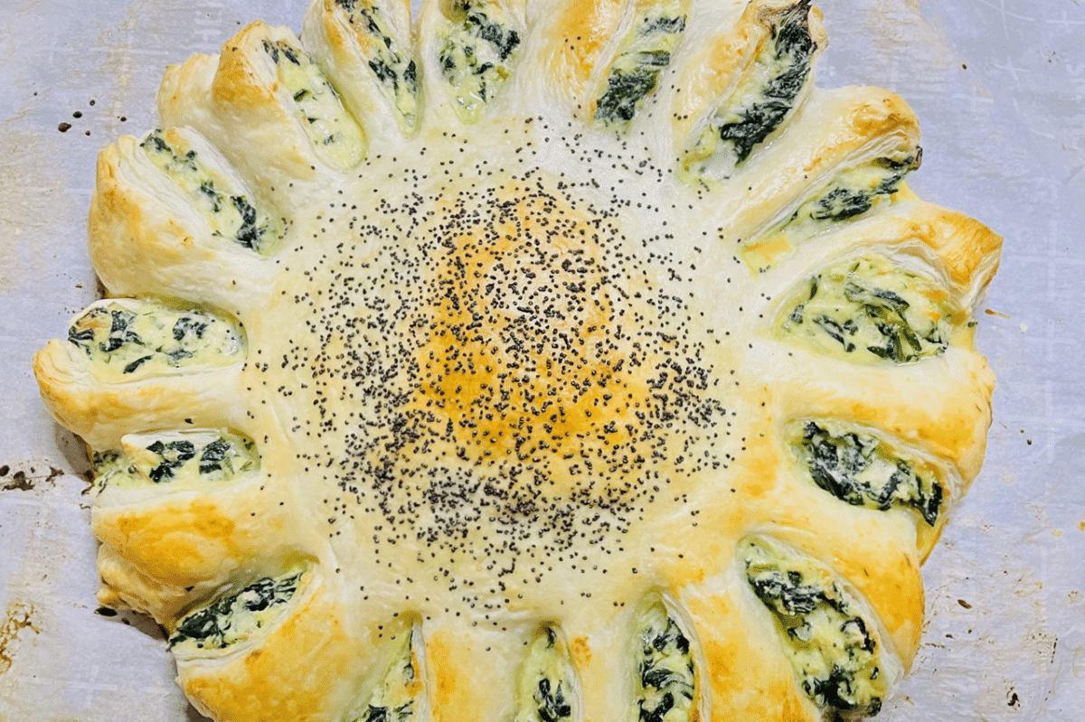Close-up of a sunflower-shaped spinach pie with sesame seeds.