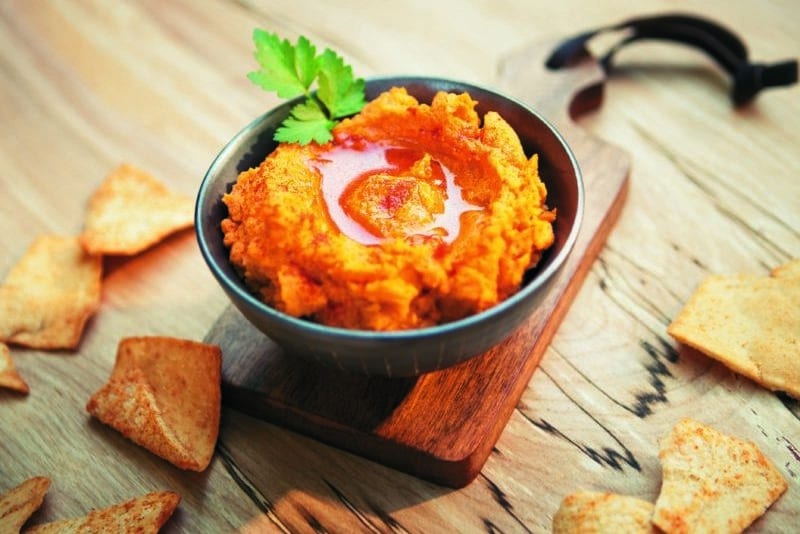Blue bowl filled with vibrant blue and green sweet potato hummus.