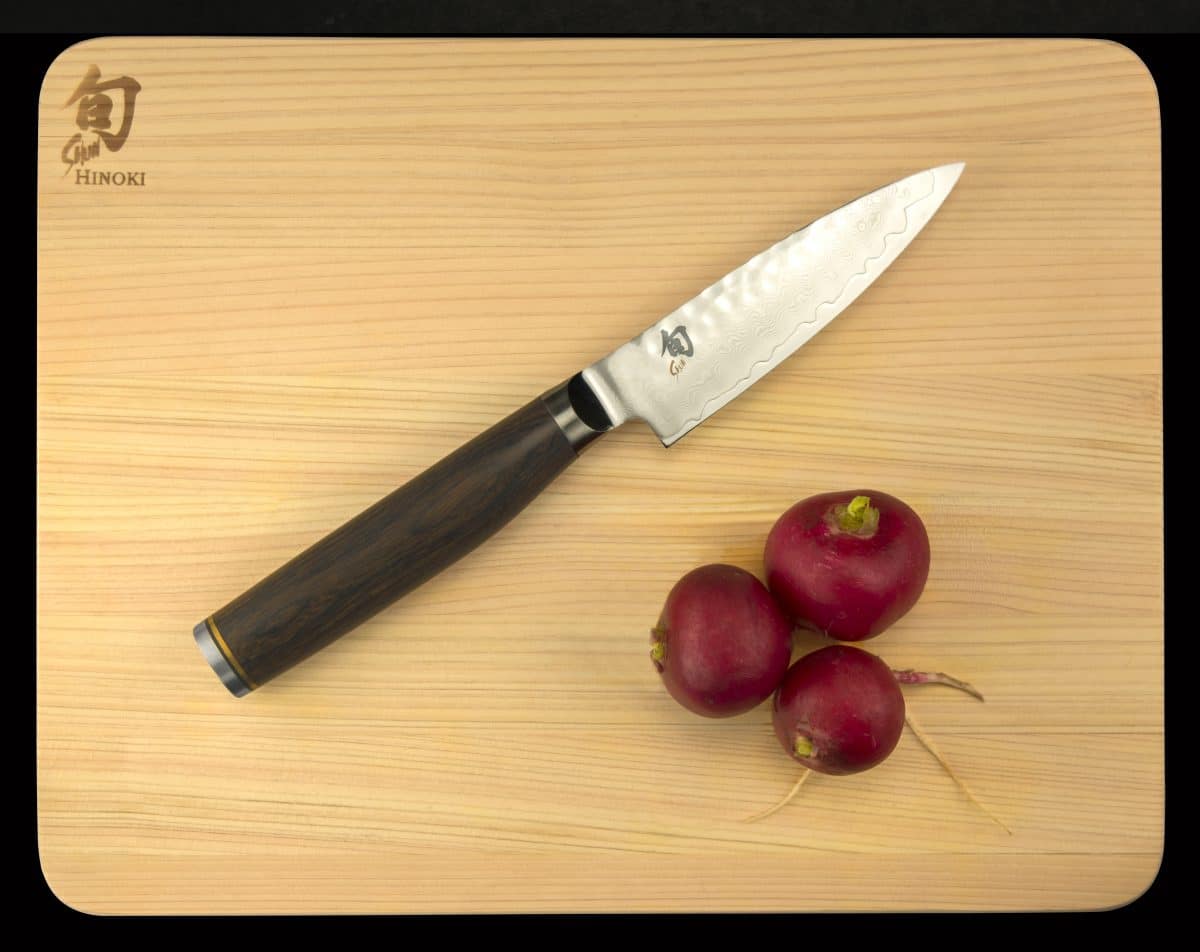 Radishes next to a Shun chef's knife on a wooden board