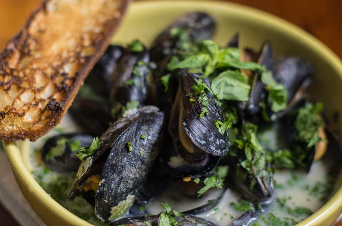 Close-up view of Thai Steamed Mussels garnished with herbs.