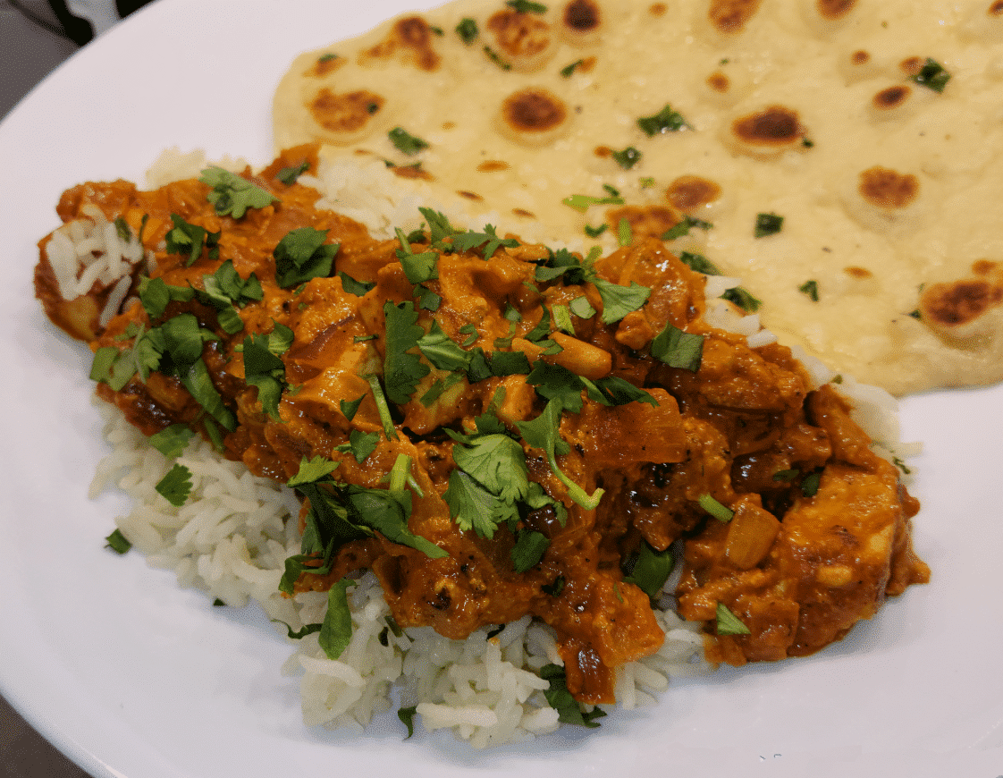 Plate of tofu tikka masala served over rice with flatbread