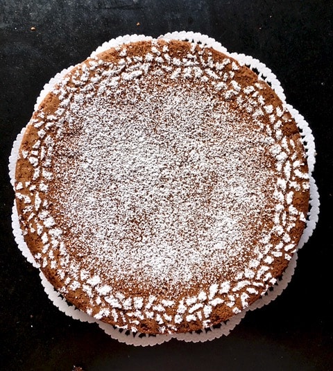 Overhead shot of a Torta Di Caprese chocolate cake, presented on a wooden backdrop with a rustic feel.
