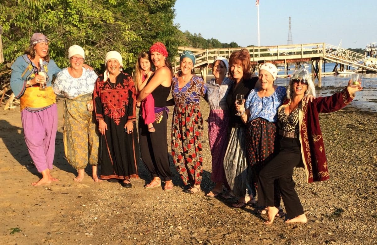 Group of friends and family in traditional Turkish attire gathering on the beach