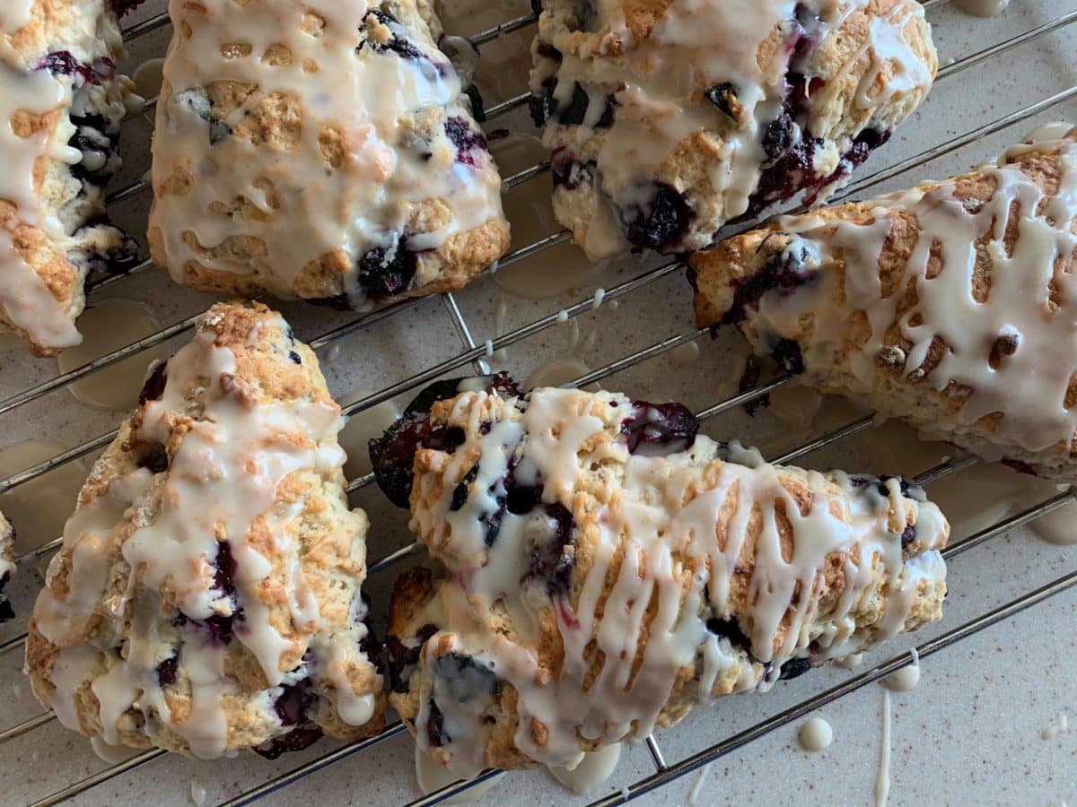 Vegan blueberry scones drizzled with glaze on a cooling rack