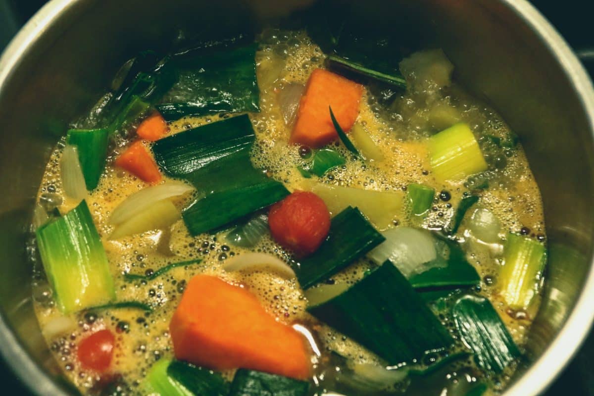Close-up of vegetable bouillon with carrots, leeks, and tomatoes.