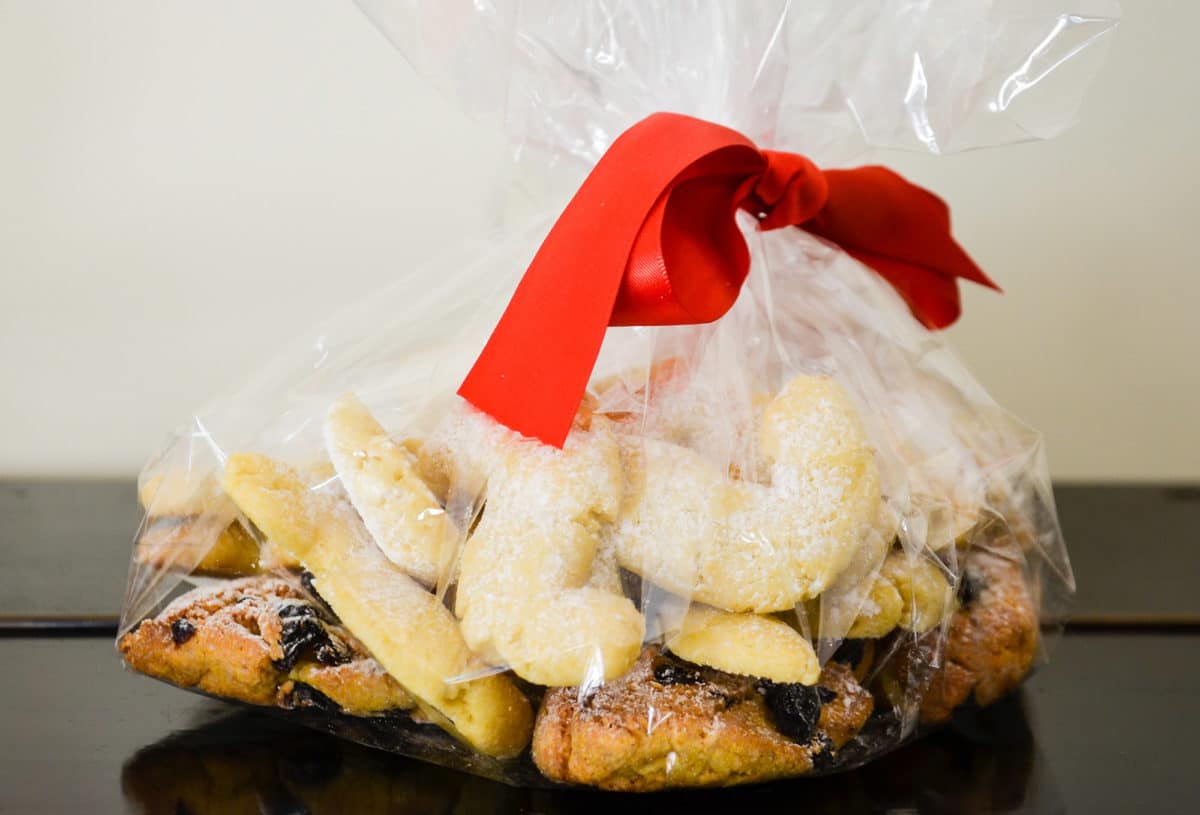 A clear plastic bag tied with a red ribbon, filled with assorted cornmeal pastries from Venice.