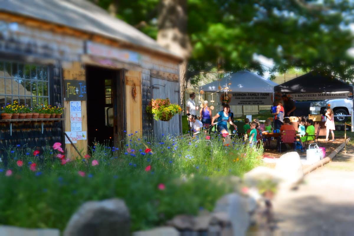People gathered outside a rustic farm store during an event.