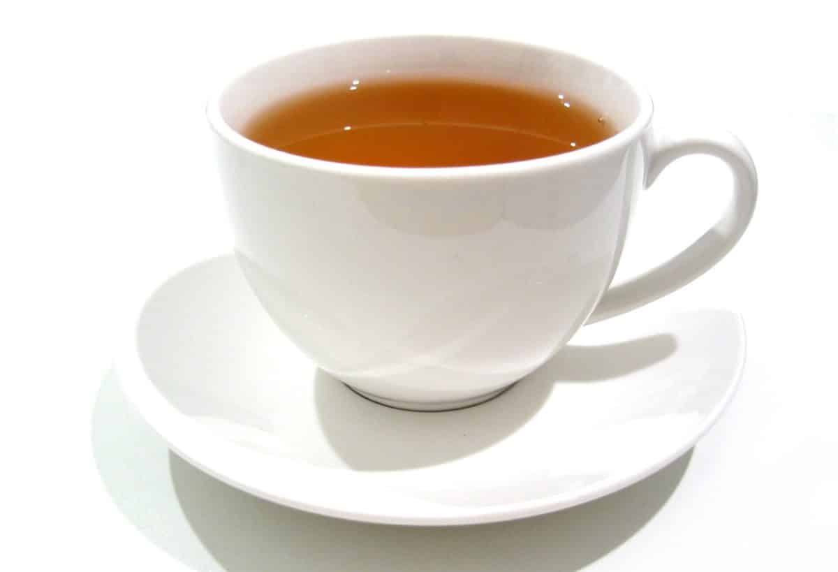 Close-up view of a white cup filled with tea on a white saucer.