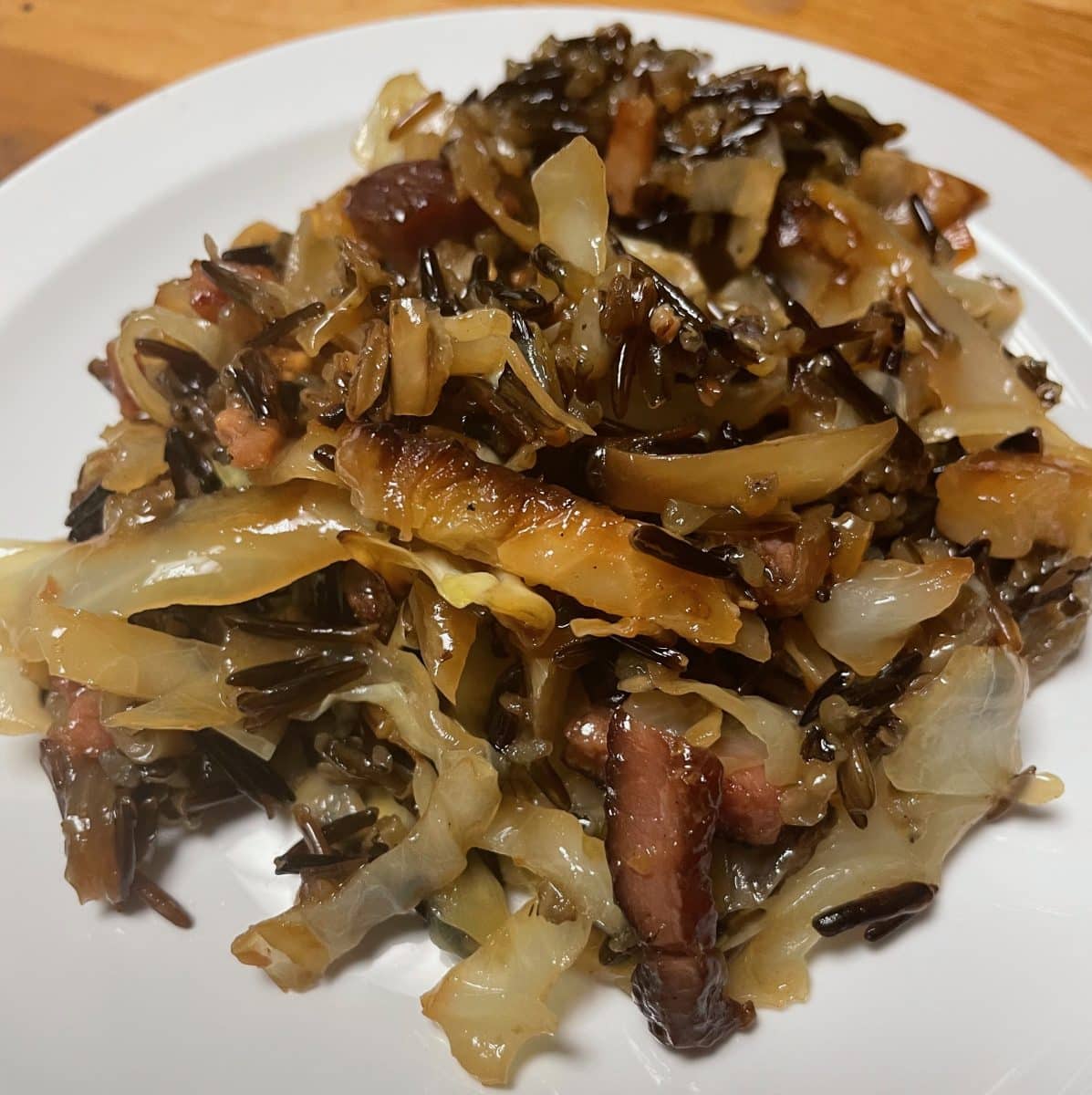 Cooked wild rice mixed with cabbage and bacon on a plate.