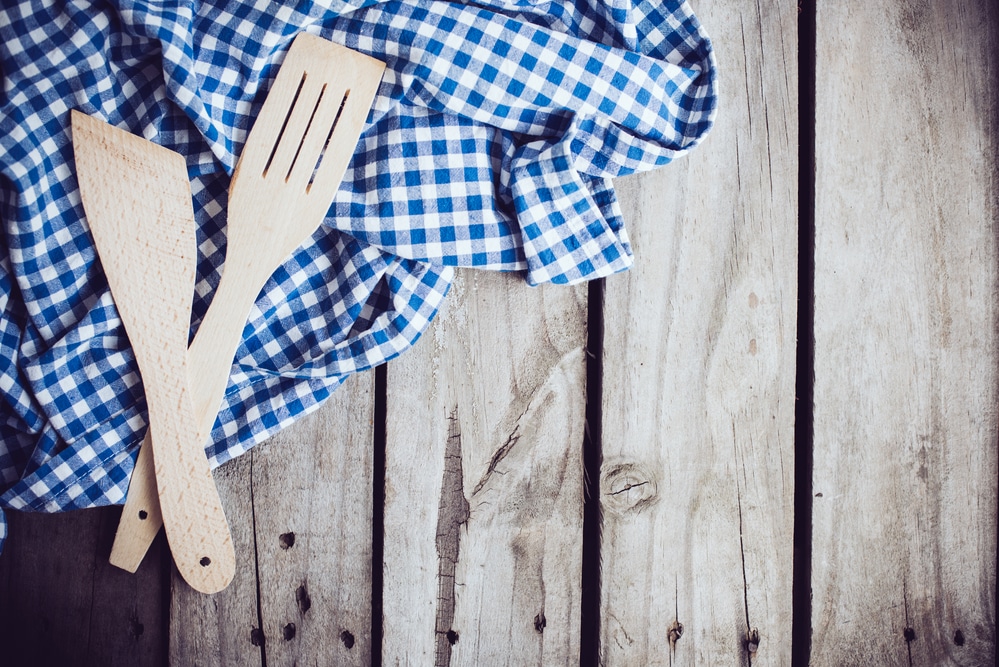 Two wooden spatulas laid out on a blue checkered cloth.