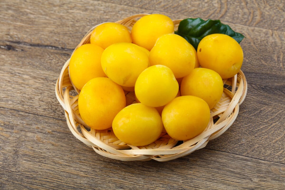 bowl of yellow plums on wooden table